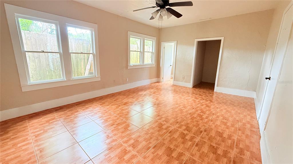 An empty room features tan walls, a ceiling fan, and orange tiled flooring — 808 NW 23RD AVENUE, GAINESVILLE, FL