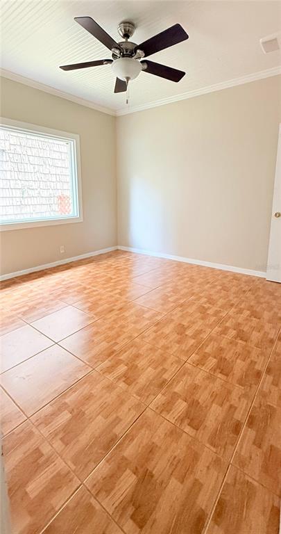 An empty room features light-colored walls, a ceiling fan, and brown square floor tiles — 808 NW 23RD AVENUE, GAINESVILLE, FL