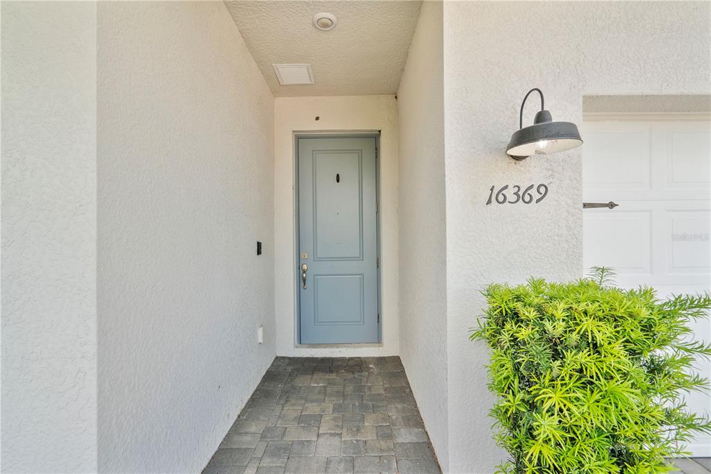 A light blue front door is set within a recessed entryway with stone paver flooring — 16369 PALMETTO STREET, PUNTA GORDA, FL