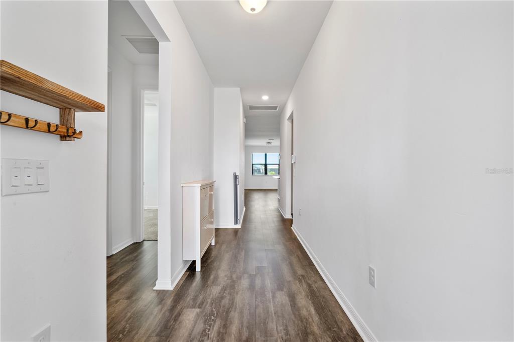 A hallway with wood-look flooring leads toward a windowed room at the end — 16369 PALMETTO STREET, PUNTA GORDA, FL