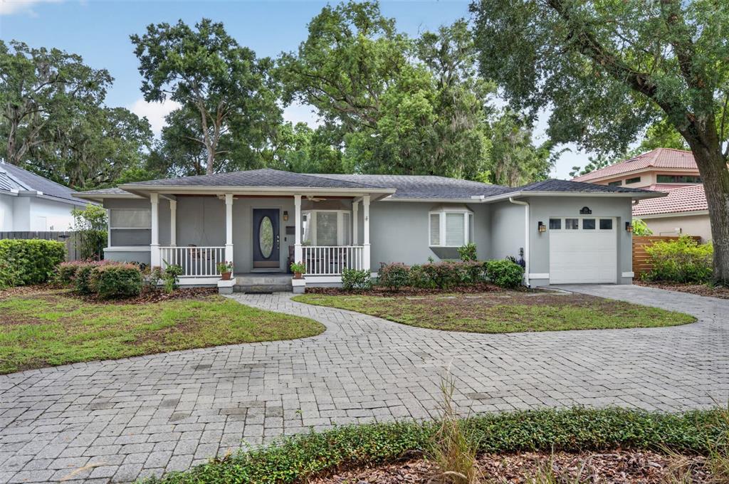 A gray single-story house features a covered front porch, a paved driveway, and mature trees — 150 E READING WAY, WINTER PARK, FL