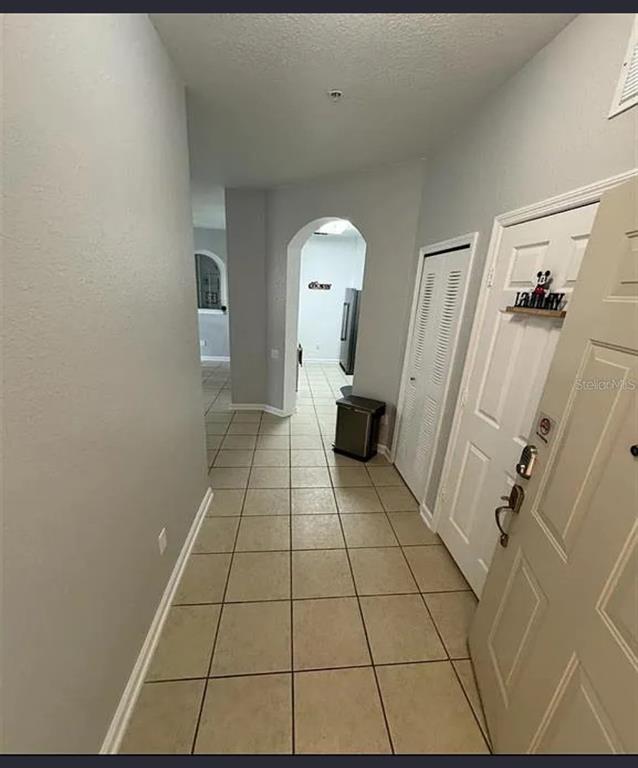 A tiled entryway leads to an arched doorway and a white door with a laundry sign — 2778 ALMATON LOOP UNIT 303, KISSIMMEE, FL