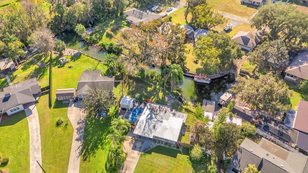 An aerial view shows several houses with pools and driveways near a small, winding canal — 8150 SPRING DRIVE, YALAHA, FL