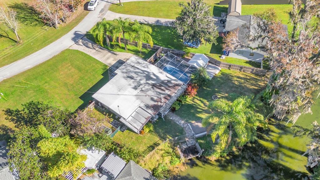 An aerial view shows a house with a pool enclosure, a dock, and a yard — 8150 SPRING DRIVE, YALAHA, FL