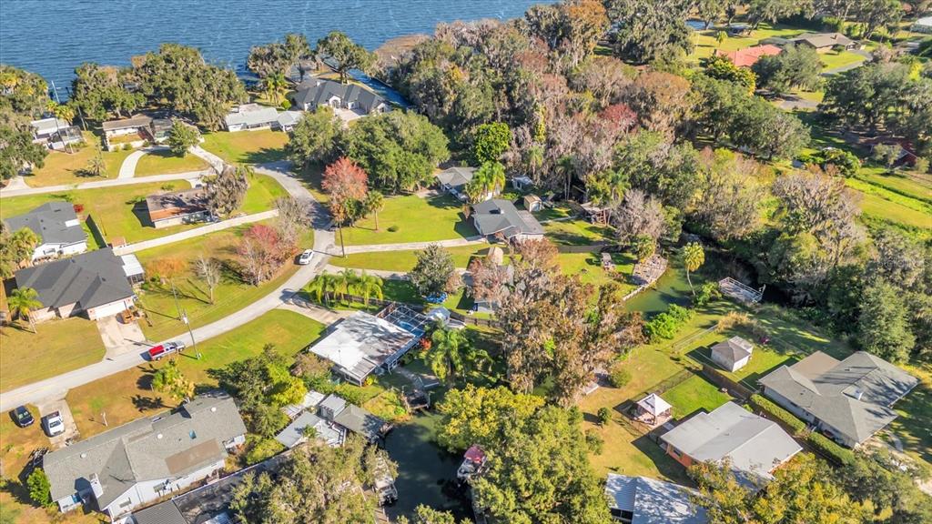Aerial view of a residential neighborhood with houses, trees, and a small canal — 8150 SPRING DRIVE, YALAHA, FL