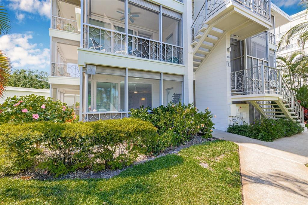The exterior of a multi-story building features screened balconies, white siding, and an outdoor staircase — 615 10TH AVENUE NE UNIT 1, ST PETERSBURG, FL