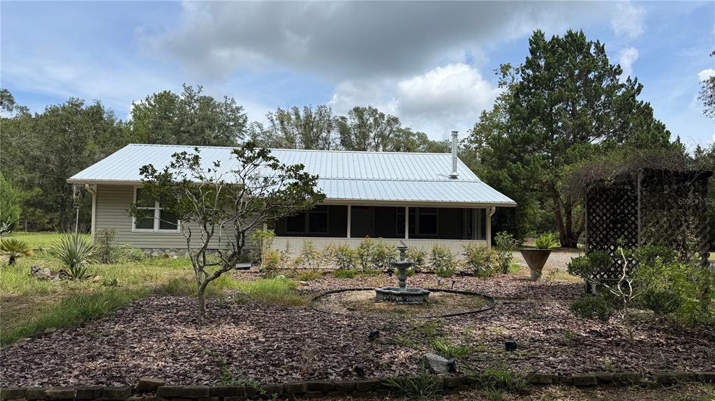 A light-colored house with a metal roof and a screened-in porch sits on a lot — 1520 BADEN POWELL ROAD, HAWTHORNE, FL