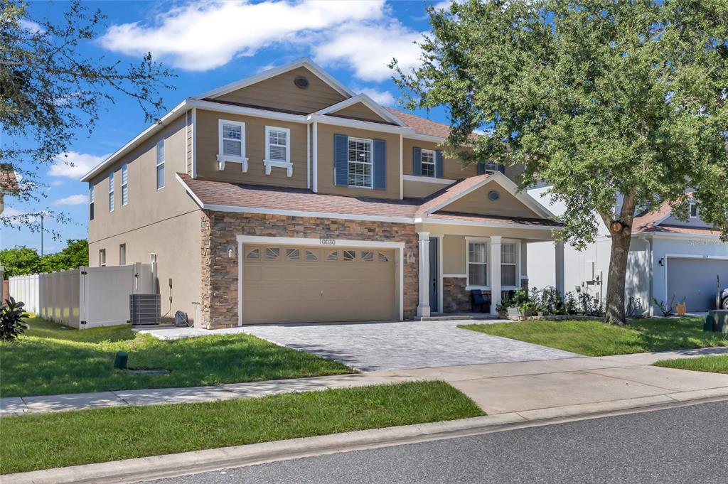 A two-story house with a stone-accented facade, a front porch, and a landscaped garden bed — 10030 STRATFORD POINTE AVENUE, ORLANDO, FL