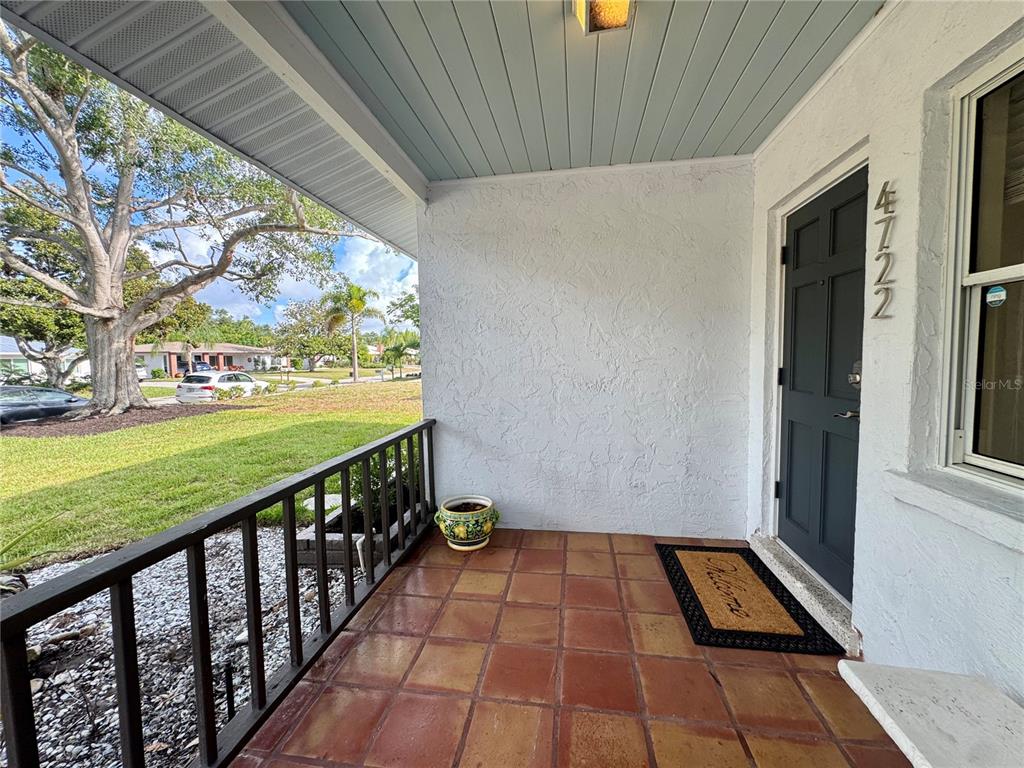 The exterior of a white house features a tiled front porch and a covered carport — 4722 STEVENS DRIVE, SARASOTA, FL