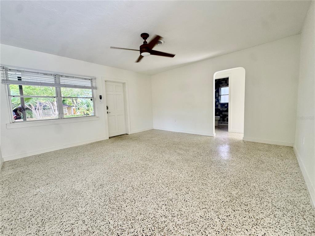 A covered front porch features terracotta tile flooring, a dark door, and a wooden railing — 4722 STEVENS DRIVE, SARASOTA, FL