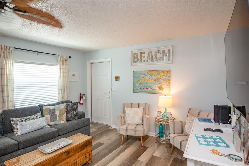 A living room features a gray sofa, two striped armchairs, and a wooden coffee table — 308 2ND STREET N UNIT 201, BRADENTON BEACH, FL