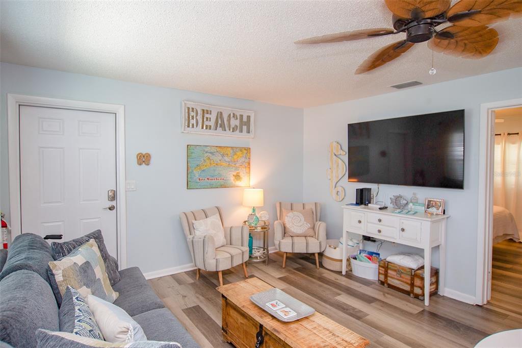 A living room features light blue walls, wood-look flooring, a ceiling fan, and coastal decor — 308 2ND STREET N UNIT 201, BRADENTON BEACH, FL