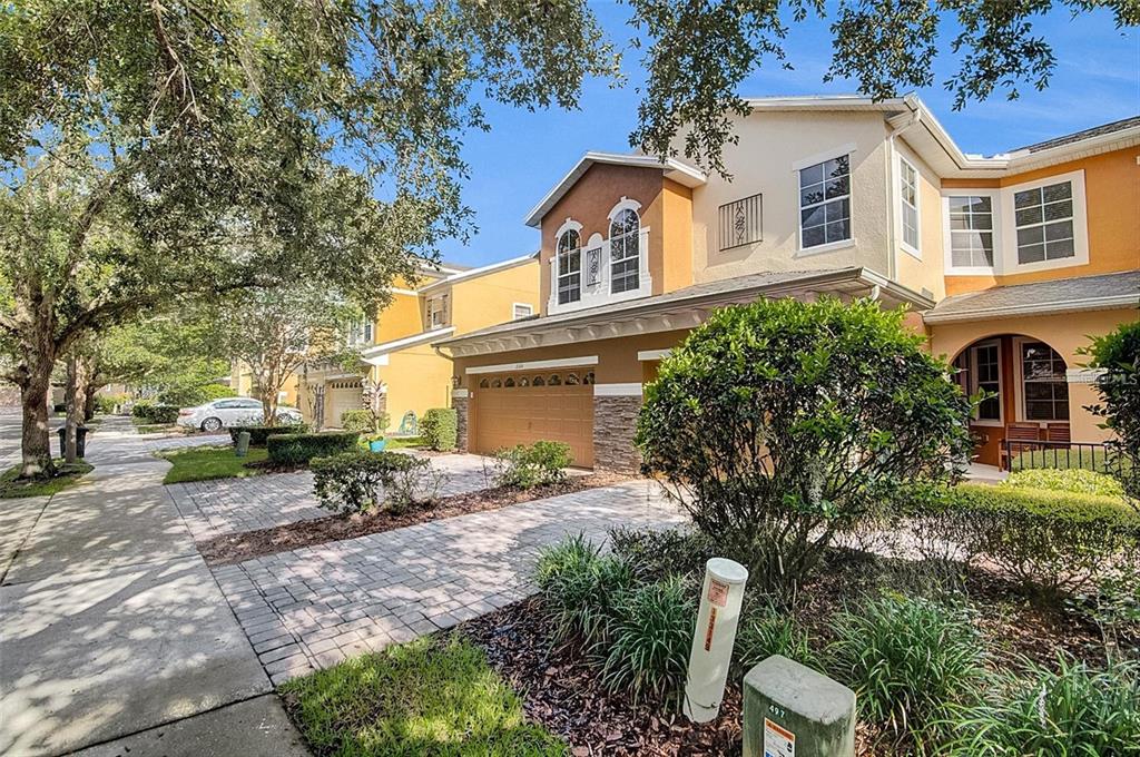 A two-story townhouse with a brown garage, stone accents, and a paved driveway — 2680 SWEET MAGNOLIA PL, OVIEDO, FL
