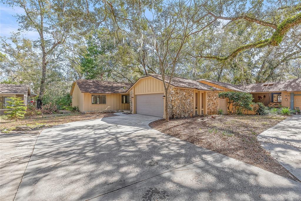 A single-story house with a stone facade, tan siding, and a concrete driveway under trees — 38 SNARESBROOK COURT, ORMOND BEACH, FL