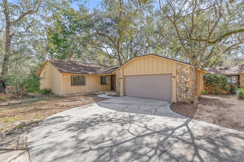 A single-story house with tan vertical siding, a stone facade, and a concrete driveway — 38 SNARESBROOK COURT, ORMOND BEACH, FL