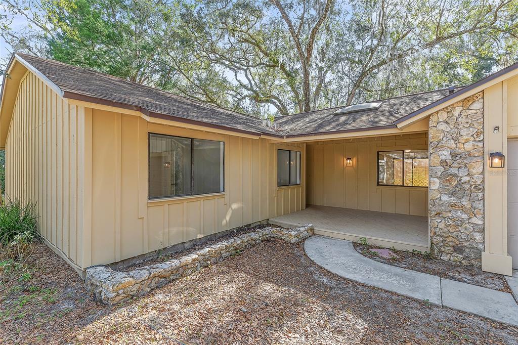 A tan house with vertical siding, a stone accent wall, and a covered front porch — 38 SNARESBROOK COURT, ORMOND BEACH, FL