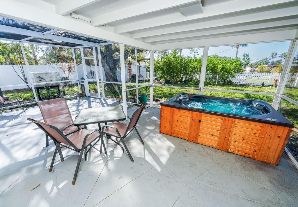 A screened-in patio with a dining set overlooks a backyard with a large tree — 301 41ST AVENUE, ST PETE BEACH, FL