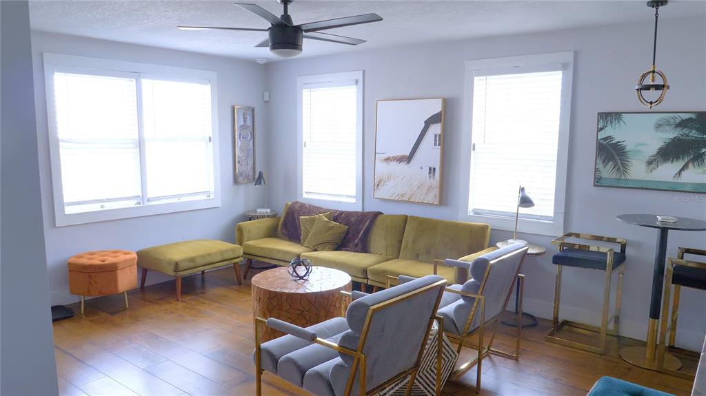 A living room features a yellow sofa, two grey armchairs, and a round wooden coffee table — 121-123 N HOLLYWOOD AVENUE, DAYTONA BEACH, FL