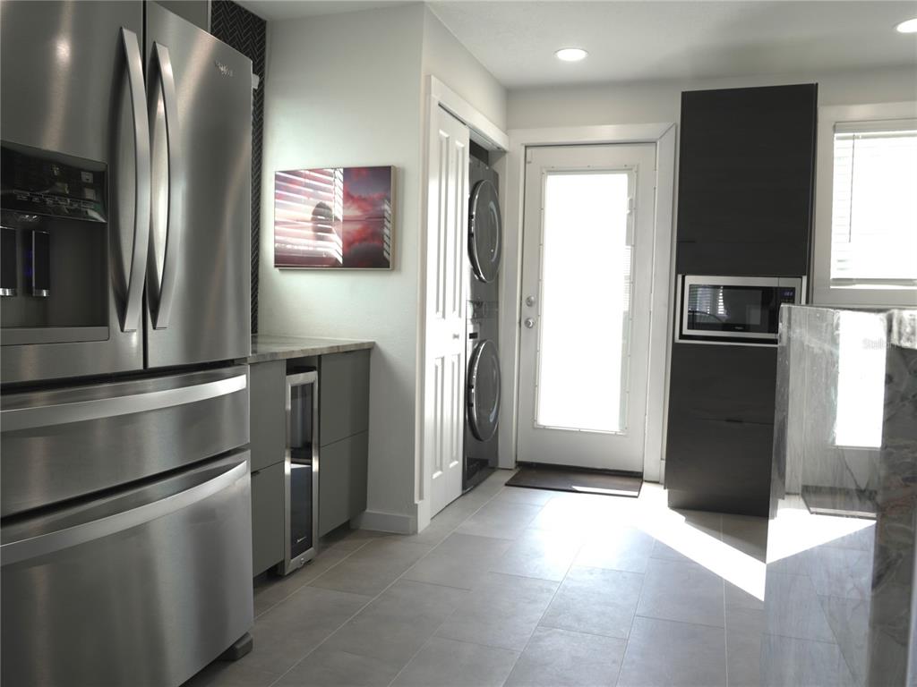 A modern kitchen features stainless steel appliances, dark cabinetry, and a stacked washer and dryer — 121-123 N HOLLYWOOD AVENUE, DAYTONA BEACH, FL