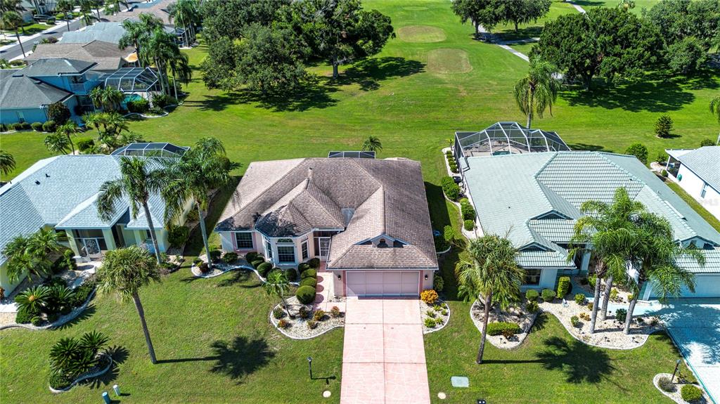 An aerial view shows a suburban house with a pink driveway and a golf course — 2424 E DEL WEBB BOULEVARD, SUN CITY CENTER, FL