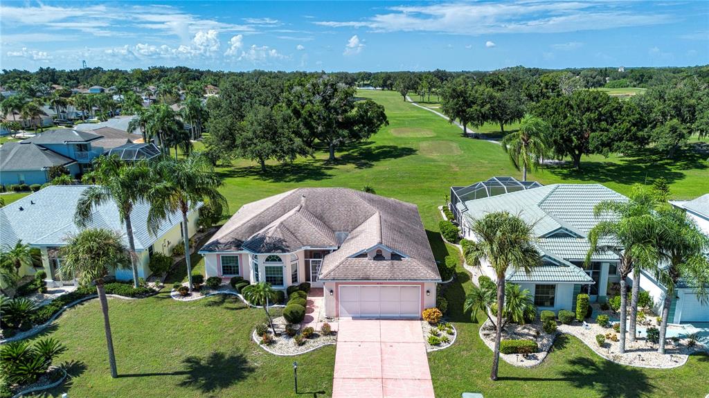 An aerial view shows a suburban house with a pink driveway and a golf course — 2424 E DEL WEBB BOULEVARD, SUN CITY CENTER, FL