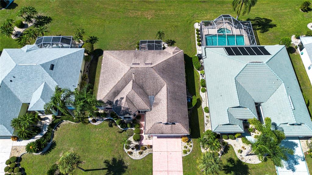 An aerial view shows three suburban houses with tiled roofs, pools, and landscaped yards — 2424 E DEL WEBB BOULEVARD, SUN CITY CENTER, FL