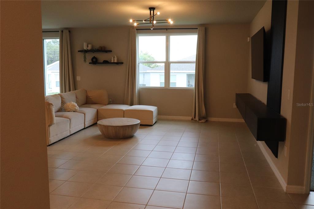 A living room features a beige sectional sofa, a round coffee table, and a wall-mounted television — 920 CAMBRIDGE DRIVE, WINTER HAVEN, FL
