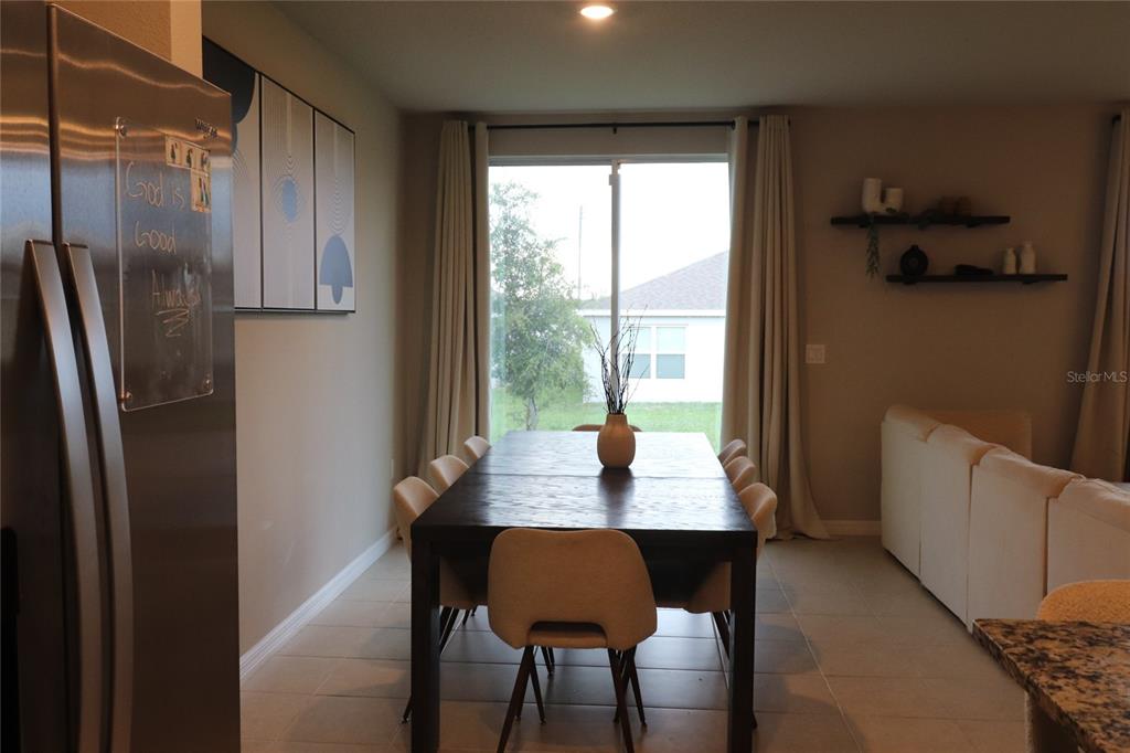 A dining room features a dark wood table, light chairs, and a sliding glass door — 920 CAMBRIDGE DRIVE, WINTER HAVEN, FL