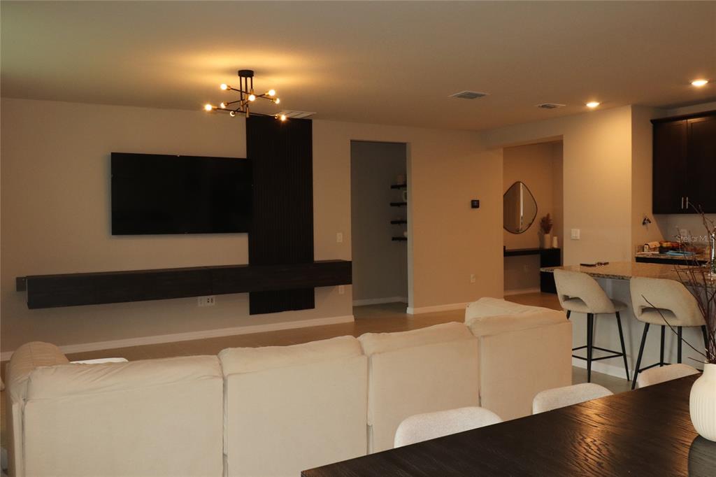 A living room features a floating media console, a wall-mounted television, and a sectional sofa — 920 CAMBRIDGE DRIVE, WINTER HAVEN, FL