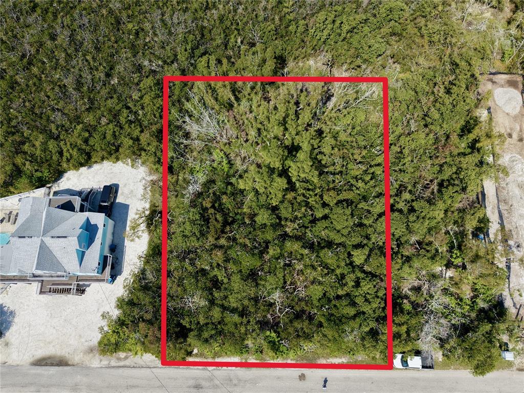 An aerial view shows a rectangular, tree-covered vacant lot outlined in red next to a house — 28TH STREET, HOLMES BEACH, FL