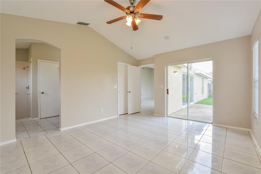 A room with light-colored tile flooring, a vaulted ceiling, a ceiling fan, and sliding doors — 1515 WOOD VIOLET DRIVE, ORLANDO, FL