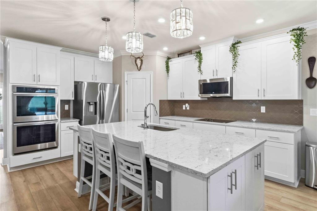A spacious open-concept living room and kitchen featuring a large sectional sofa and wood flooring — 10007 DOLPHIN GULL CIRCLE, THONOTOSASSA, FL