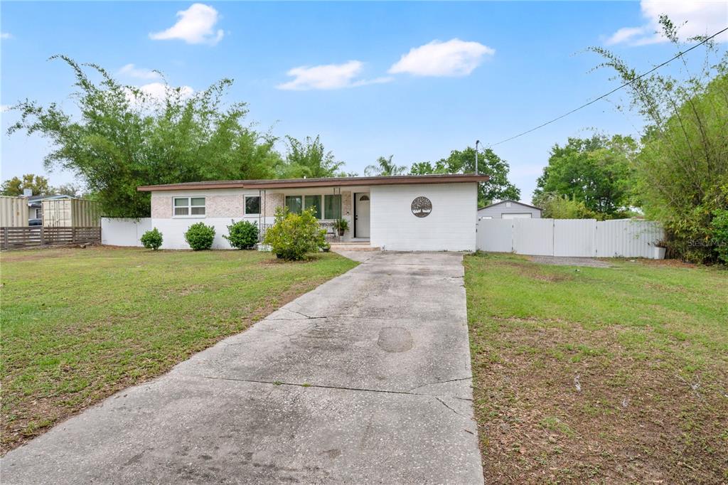 A single-story white house with a concrete driveway and a large front yard — 2010 LEE DRIVE, VALRICO, FL