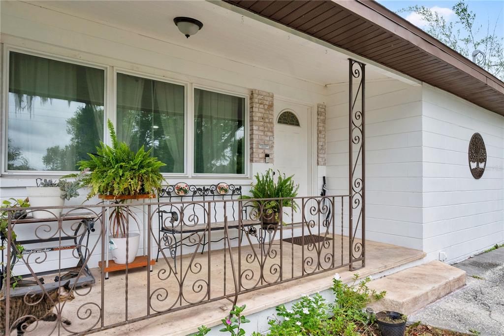 A white house exterior features a front porch with decorative metal railings and a bench — 2010 LEE DRIVE, VALRICO, FL