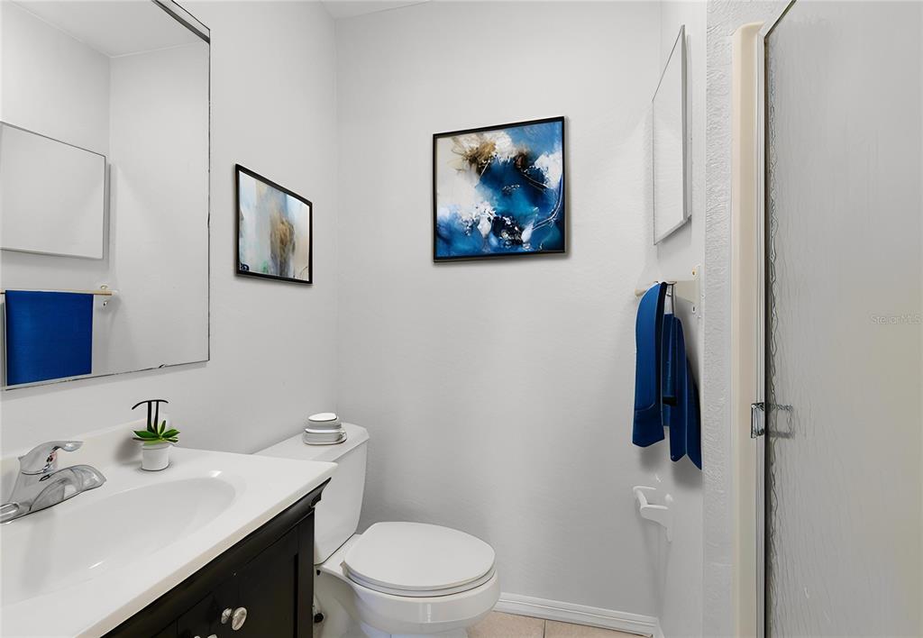 A bathroom features a vanity with a dark cabinet, a toilet, and a glass-enclosed shower — 1040 S BUENA VISTA DRIVE UNIT 1040, LAKE ALFRED, FL