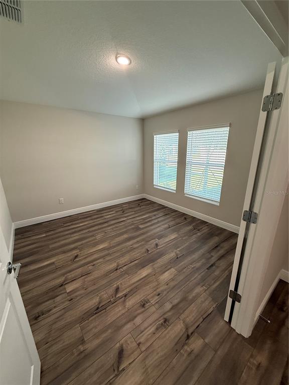 An empty room with light-colored walls, wood-look flooring, and two windows with white blinds — 9924 ANNUNCIATION DRIVE, WESLEY CHAPEL, FL