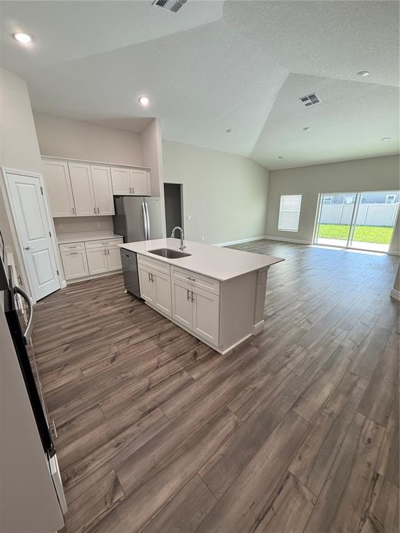 A kitchen with white cabinets and a center island opens into a spacious living area — 9924 ANNUNCIATION DRIVE, WESLEY CHAPEL, FL