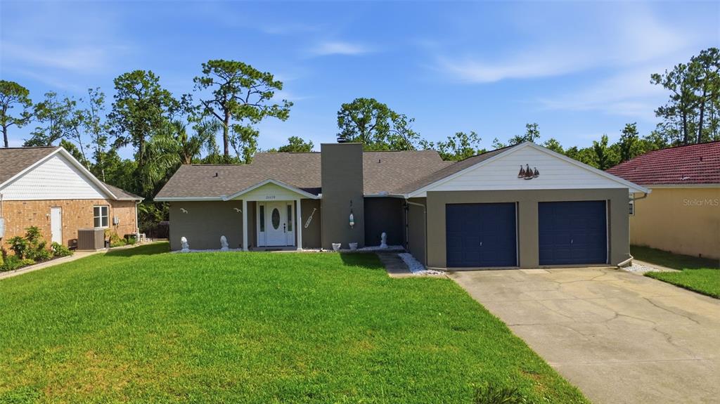 A single-story house with a gray exterior, two garage doors, and a front lawn — 26638 E COVE DRIVE, TAVARES, FL