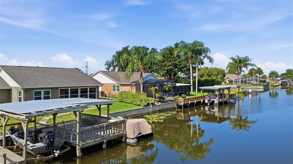 A canal-front house with a boat dock and covered boat lift under a blue sky — 26638 E COVE DRIVE, TAVARES, FL