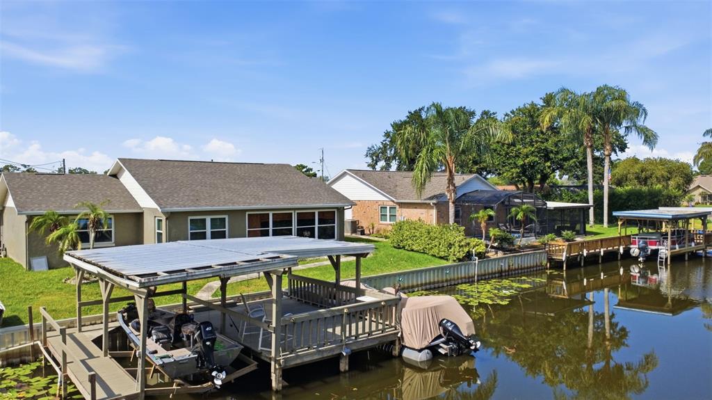 An exterior view shows two waterfront houses with boat docks on a canal — 26638 E COVE DRIVE, TAVARES, FL