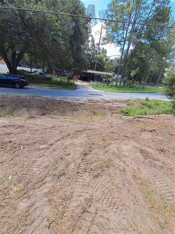 A view of a cleared, sandy lot looking toward a paved road and neighboring houses — 5601 NW 71ST STREET, OCALA, FL