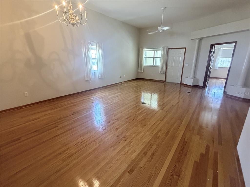 A spacious room features hardwood floors, a chandelier, a ceiling fan, and white walls — 2784 ALEXANDER DRIVE, CLEARWATER, FL