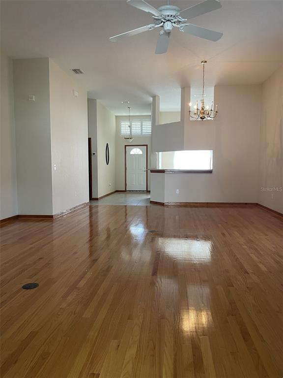 A spacious living area features hardwood floors, a ceiling fan, and a chandelier — 2784 ALEXANDER DRIVE, CLEARWATER, FL