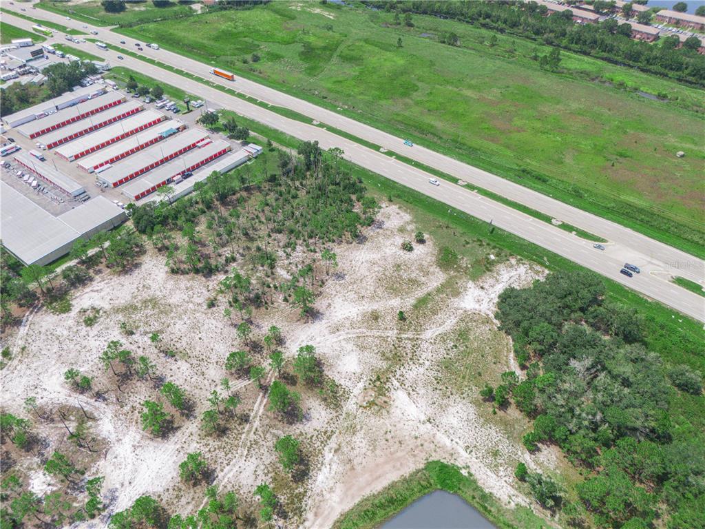 An aerial view shows a vacant, sandy lot adjacent to a highway and storage facility — US-27, LAKE WALES, FL