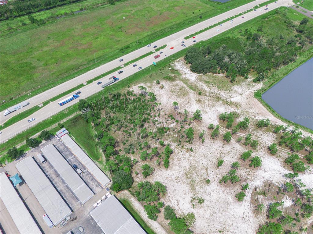 An aerial view shows a vacant lot next to a warehouse complex and a highway — US-27, LAKE WALES, FL