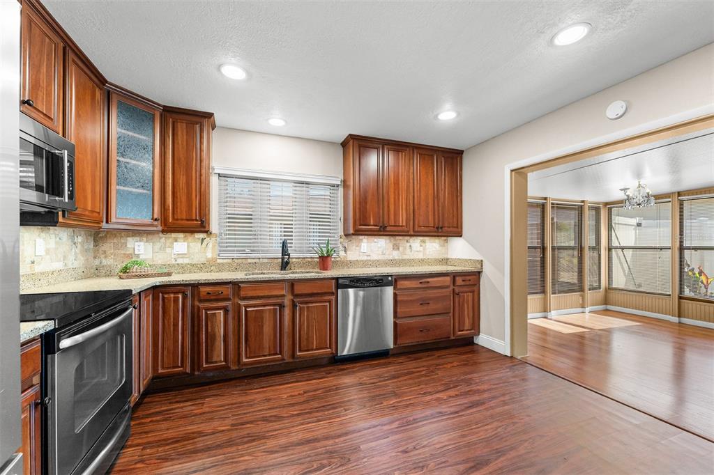 A kitchen with wood cabinets, granite countertops, stainless steel appliances, and wood-look flooring — 145 MAYFAIR COURT UNIT 145, SANFORD, FL