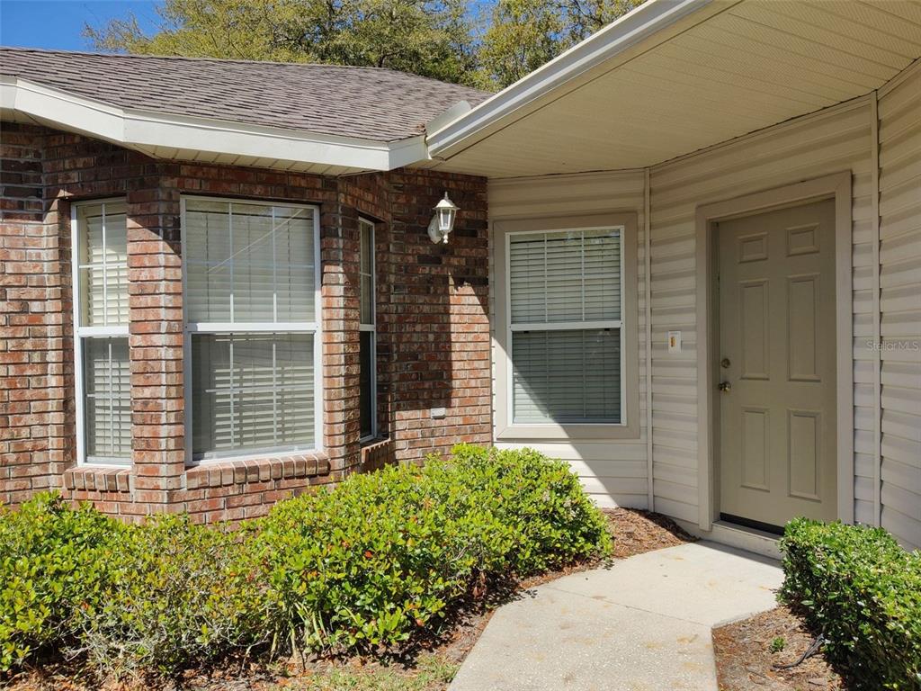 A brick and siding house exterior features a front door, windows, and a landscaped walkway — 4806 NW 77TH ROAD, GAINESVILLE, FL