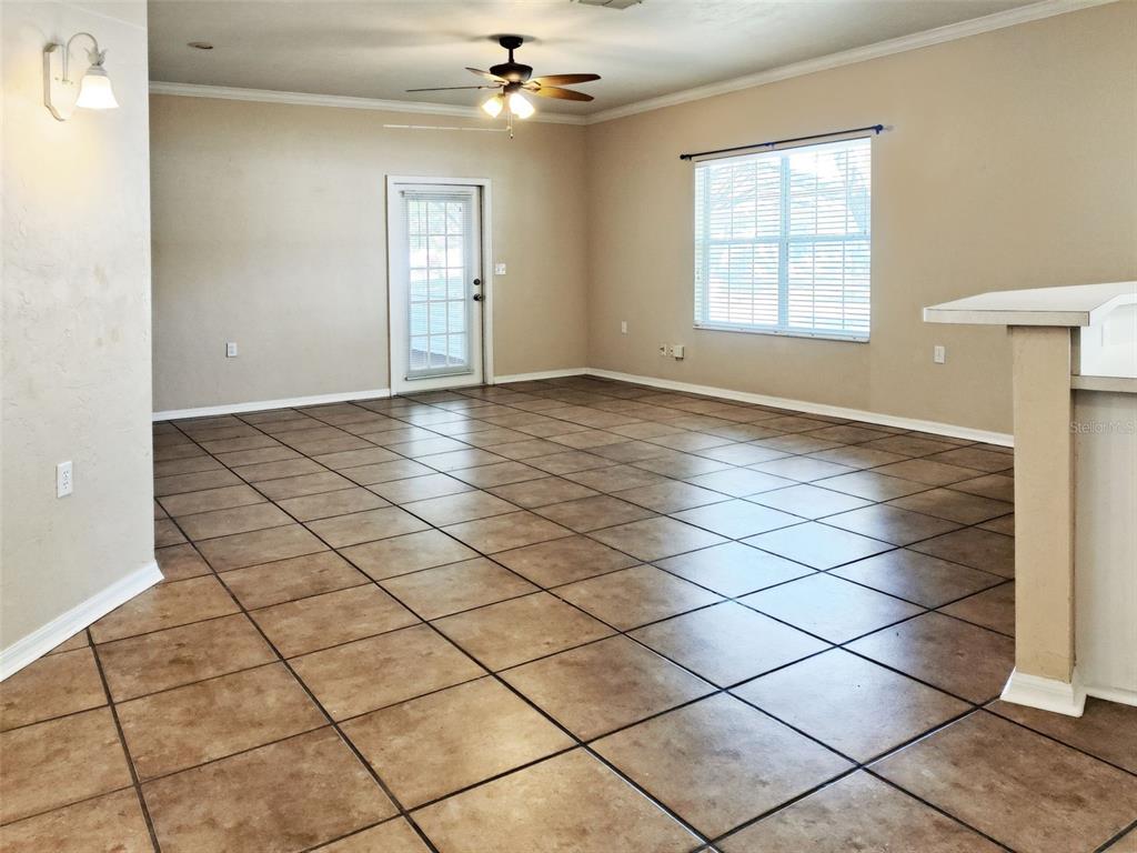 An empty room with tan walls, brown tile flooring, a ceiling fan, and a glass door — 4806 NW 77TH ROAD, GAINESVILLE, FL