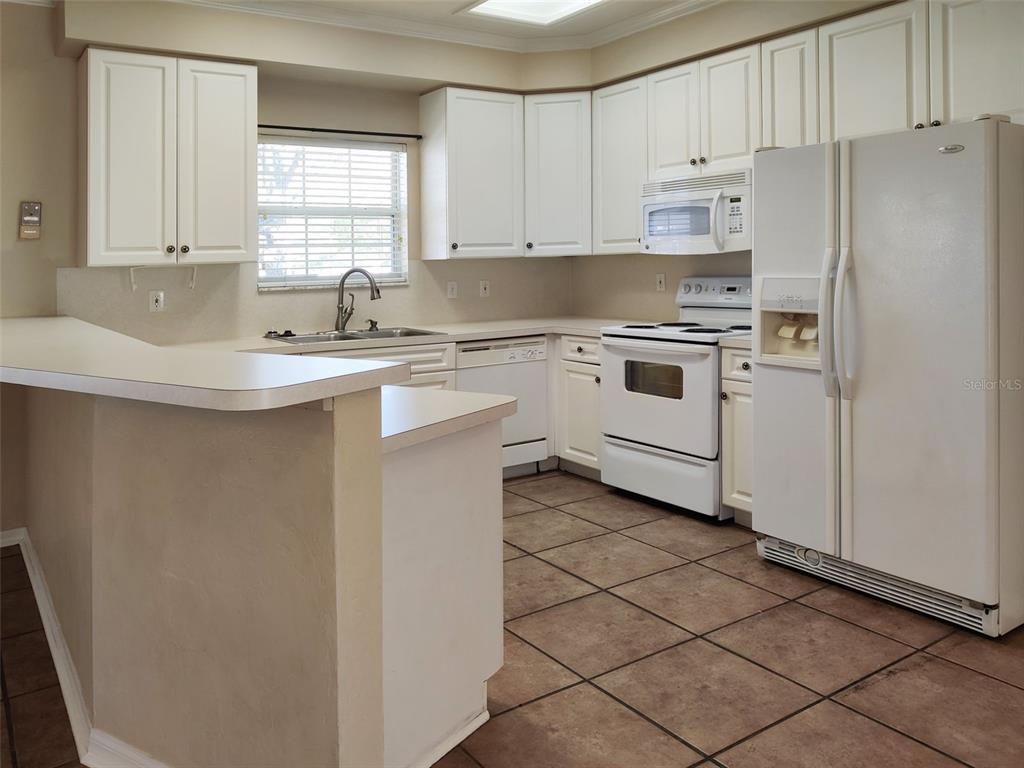 A kitchen with white cabinets, white appliances, and tan tile flooring — 4806 NW 77TH ROAD, GAINESVILLE, FL