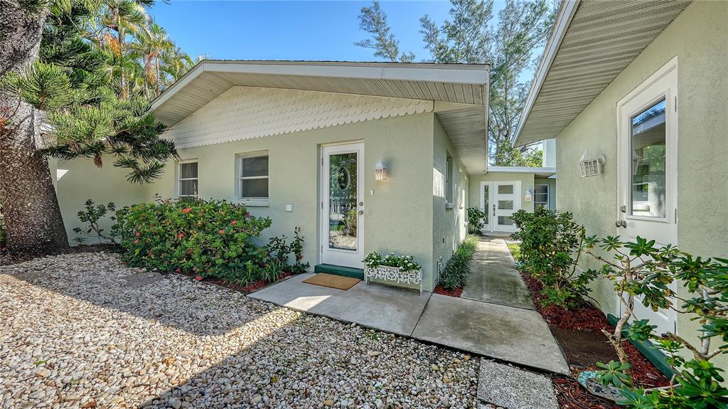 A light green house exterior features a gravel yard, a concrete walkway, and white trim — 120 HAMMOCK ROAD, ANNA MARIA, FL